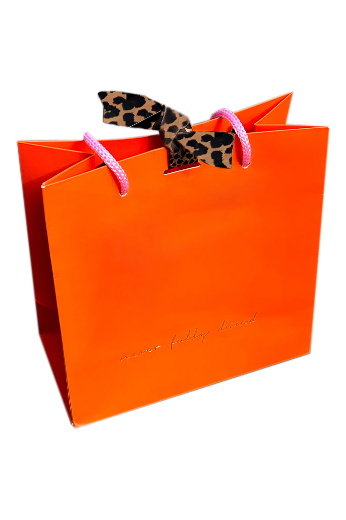 Vibrant orange gift bag featuring gold foil NFD branding, pink handles, and signature leopard print ties.