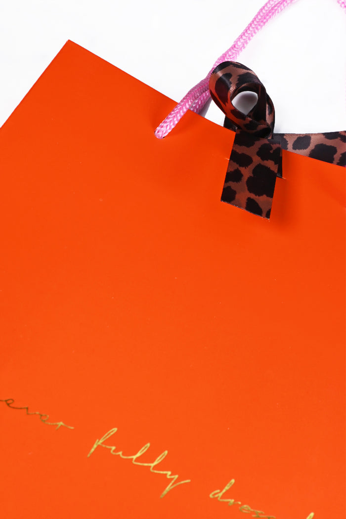 Orange NFD gift bag featuring gold foil branding, signature leopard print ties and pink cord handles.