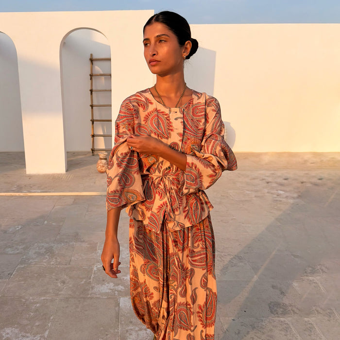 Peach Paisley Anna Top with a tie waist and matching balloon trousers in a sunlit courtyard.