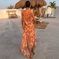 Peach Paisley Ava Dress with a low cowl back and bias-cut maxi silhouette, styled in an outdoor vacation setting.