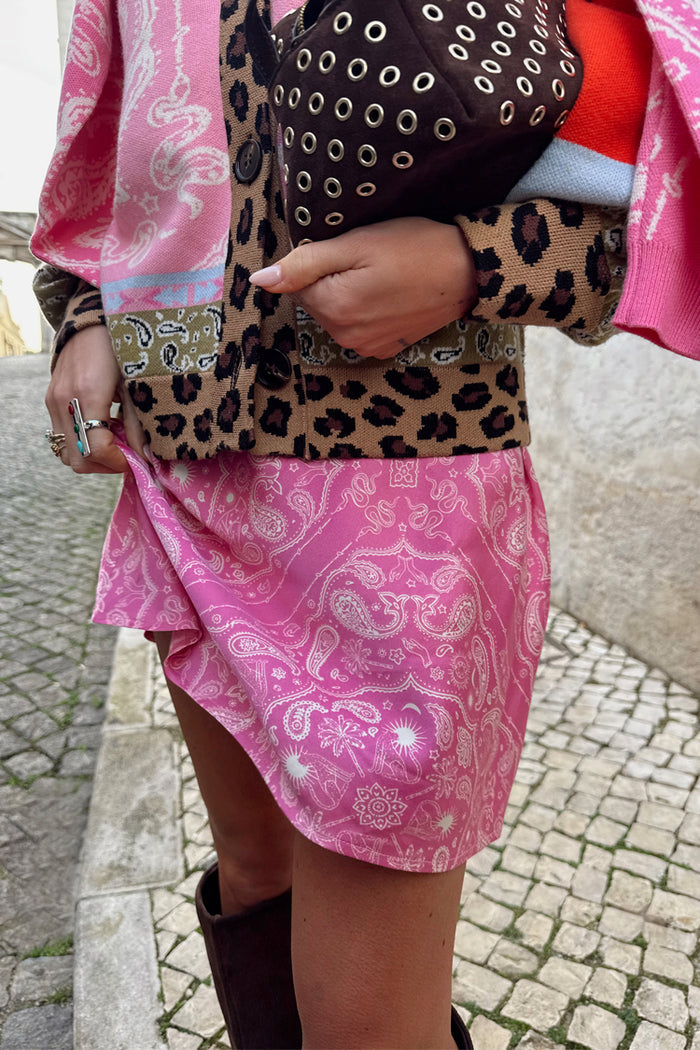 Pink Bandana Mini Dorris Skirt featuring a white paisley print, styled with a leopard print cardigan on a cobbled street.