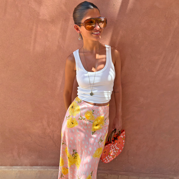 Pink Fawn Poppy Maeva Midi Skirt featuring yellow floral and deer prints, styled with a white ribbed vest.