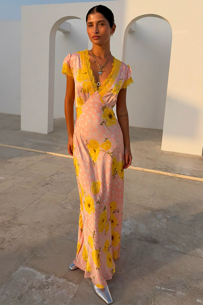 Pink Fawn Poppy Olivia Midaxi Dress with yellow lace trim and floral motifs on a model by white arches.