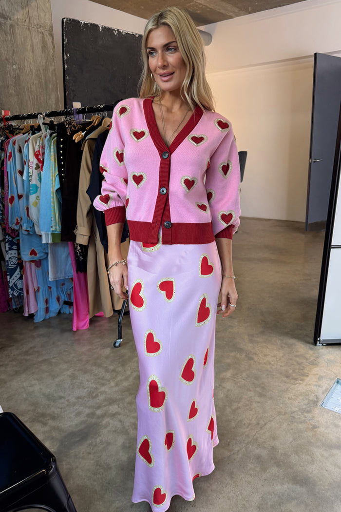 Knitted Pink Hearts Cardigan with red heart motifs and contrast trims, paired with a matching heart print slip skirt.