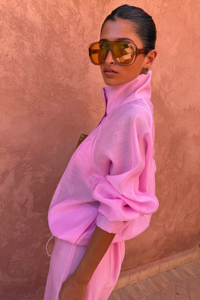 Pink Organza Funnel Jacket in semi-sheer fabric with a funnel collar and oversized sunglasses against a textured wall.