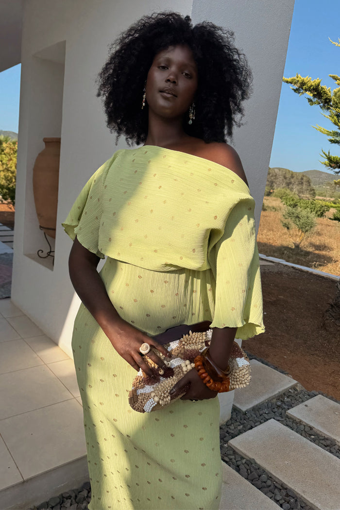 Pistachio Tilly Dress in green plisse with gold flecks, featuring off-the-shoulder styling for wedding guest season.