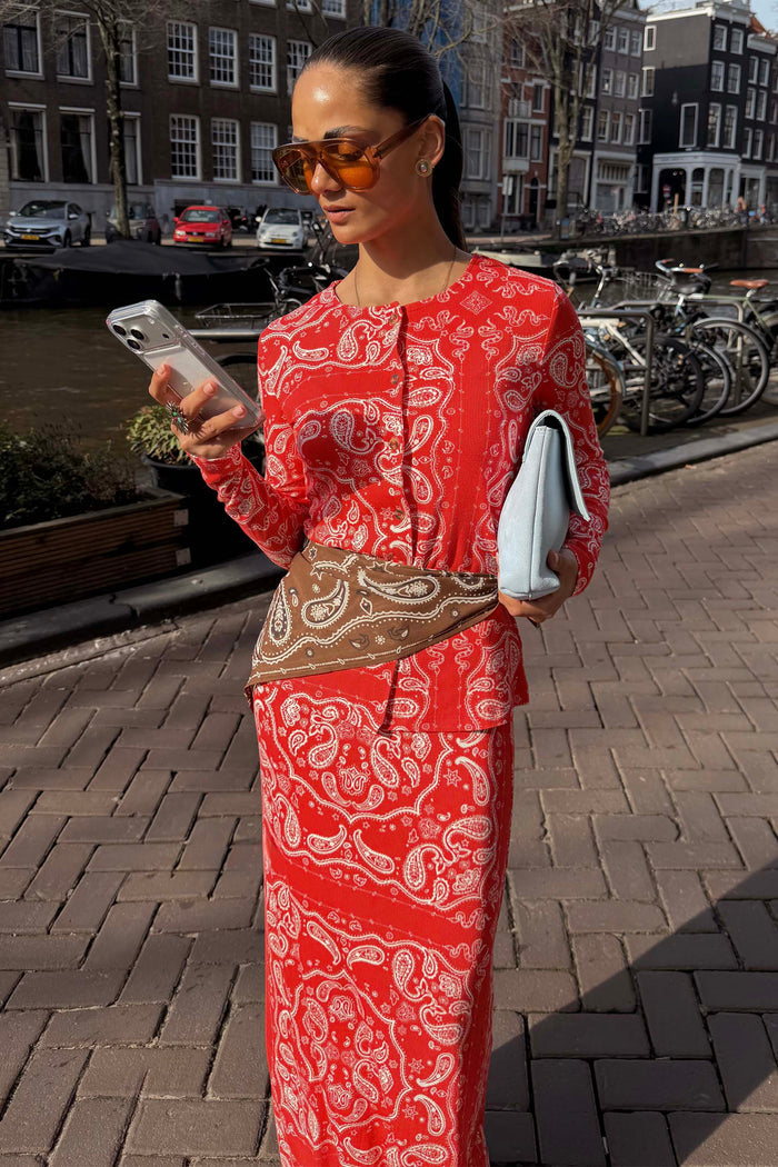 Iconic Red Bandana Alexa Cardigan in a ribbed knit, styled as a co-ord with a matching skirt and light blue clutch.