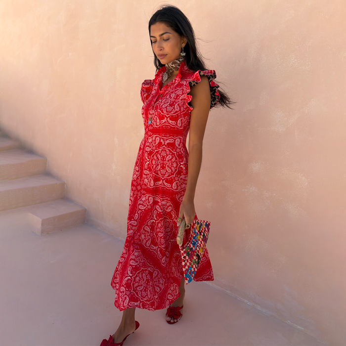 Red bandana Remi dress with leopard print sleeves, a pleated neckline and asymmetrical skirt on a model.
