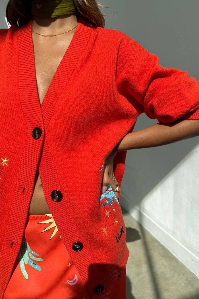 Red Celestial Cardigan in a soft knit with embroidered palm and star motifs, worn with a matching co-ord skirt.