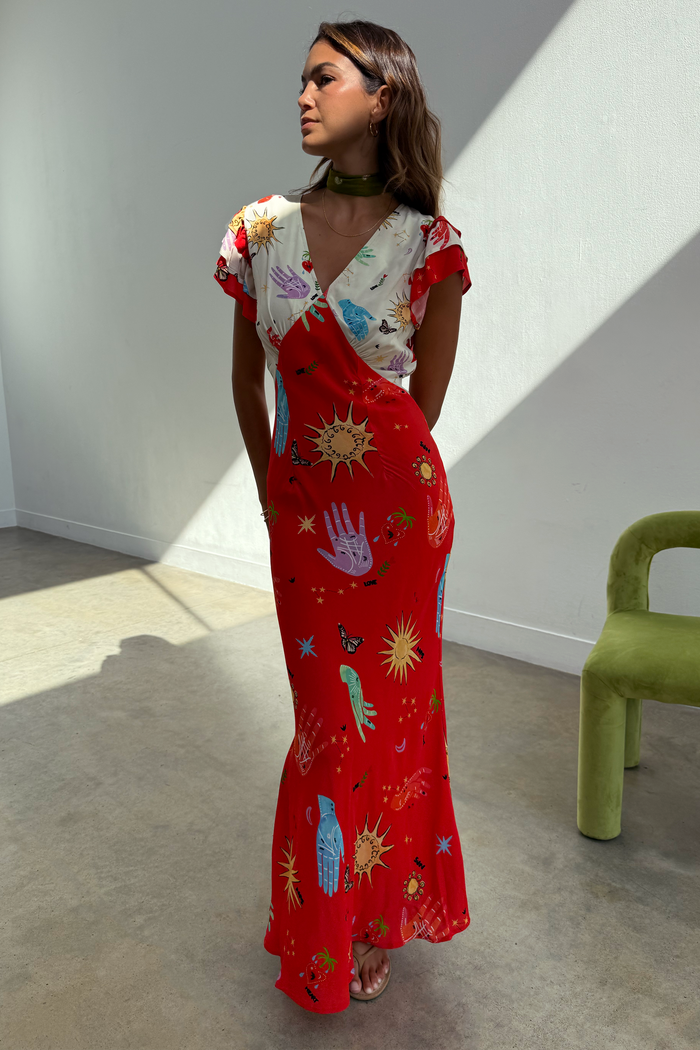 Red and cream Celestial Midi Dress with a sun and hand print, V-neck blouson top and bias-cut skirt on a model.
