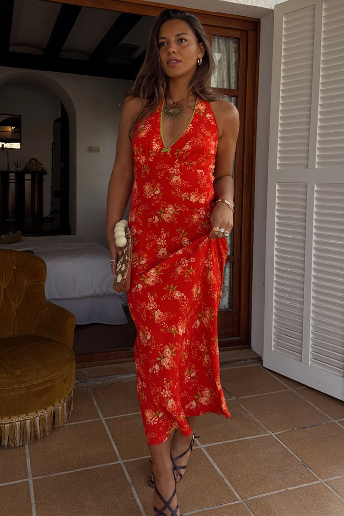 Red floral halter dress featuring a pink and green print with green trim and neck bow detail.