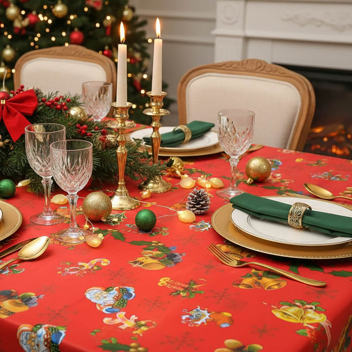 Christmas dinner table set with a red tablecloth with gold bells wine glasses and gold cutlery