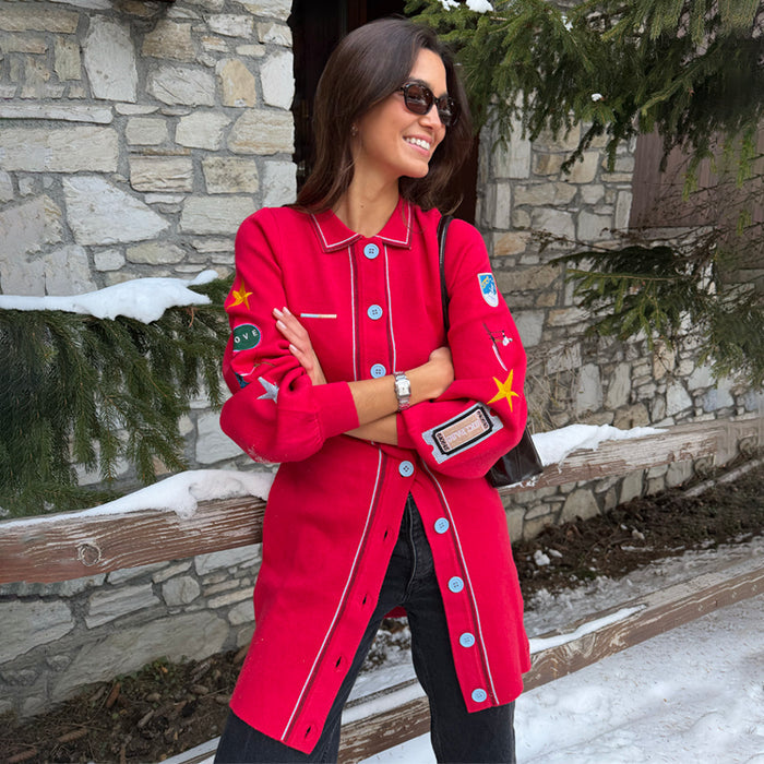 Red Ski Knit Long Cardigan featuring embroidered motifs and blue buttons, styled for a snowy vacation.