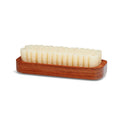 A crepe suede brush with a beige bristle head and a brown exotic wood handle.