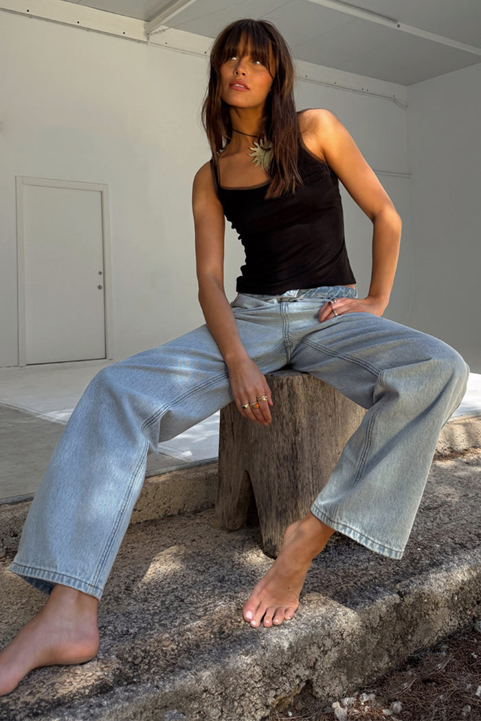 Blue Scallop Detail Straight Leg Jeans and a black vest top on a model sitting on a wooden stump.