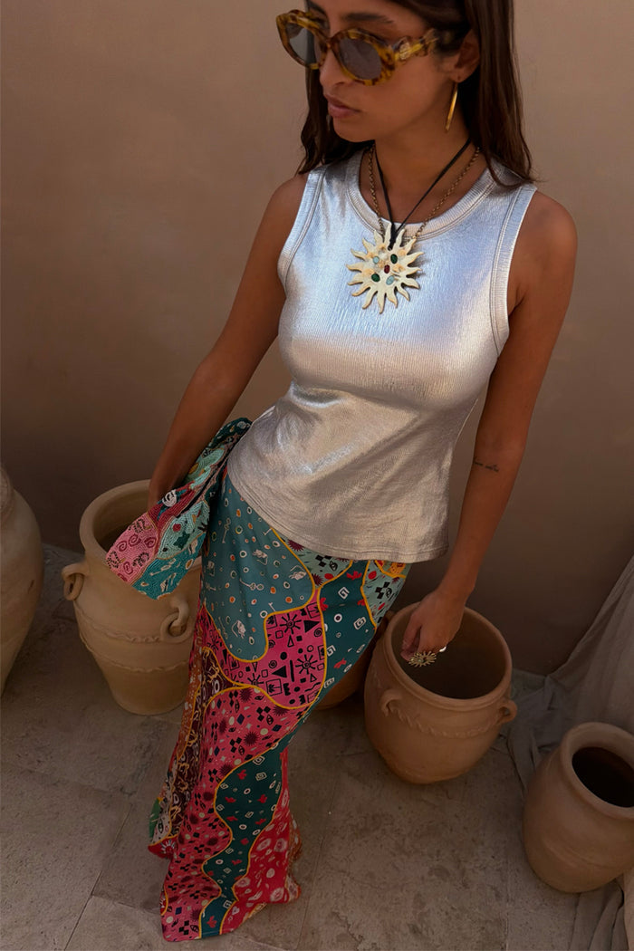 Metallic silver ribbed tank top styled with a colourful patterned skirt and sun necklace.