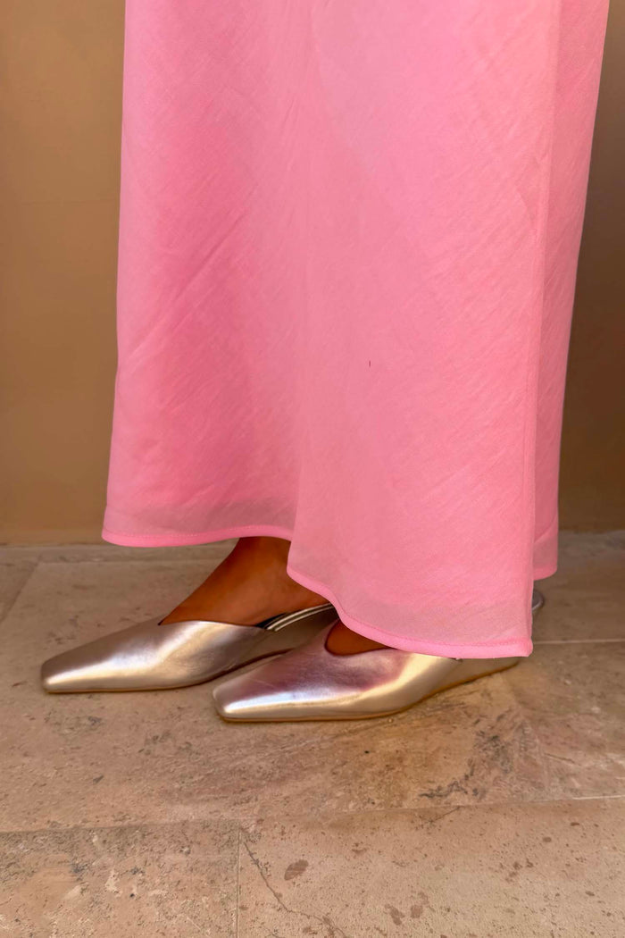 Silver Wedge Mule in metallic leather with a pointed toe and sculpted wedge heel, worn with a pink skirt.