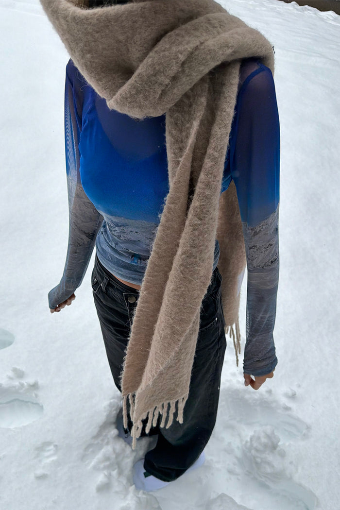 Blue Ski Slopes Mesh Long Sleeve Top with a mountain print, styled with a tan scarf and black jeans in the snow.