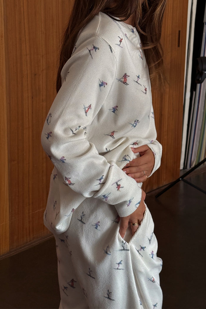 White textured Ski Waffle Pyjamas with a multi-coloured ski print, featuring a long-sleeved top and side pockets.