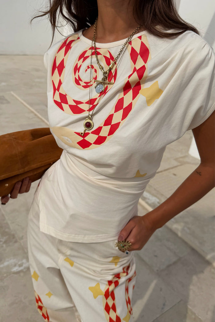Snake Asymmetric Top in white with red and yellow snake print, star motifs and a gathered waist.
