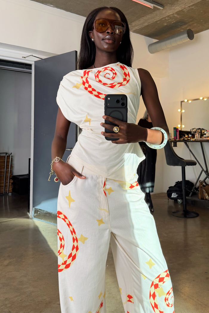 White Snake Asymmetric Top with red snake and star motifs, styled as a co-ord in a mirror selfie.