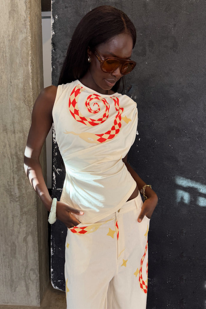 Snake Asymmetric Top in white with a red chequered snake print and star motifs, paired with matching trousers.