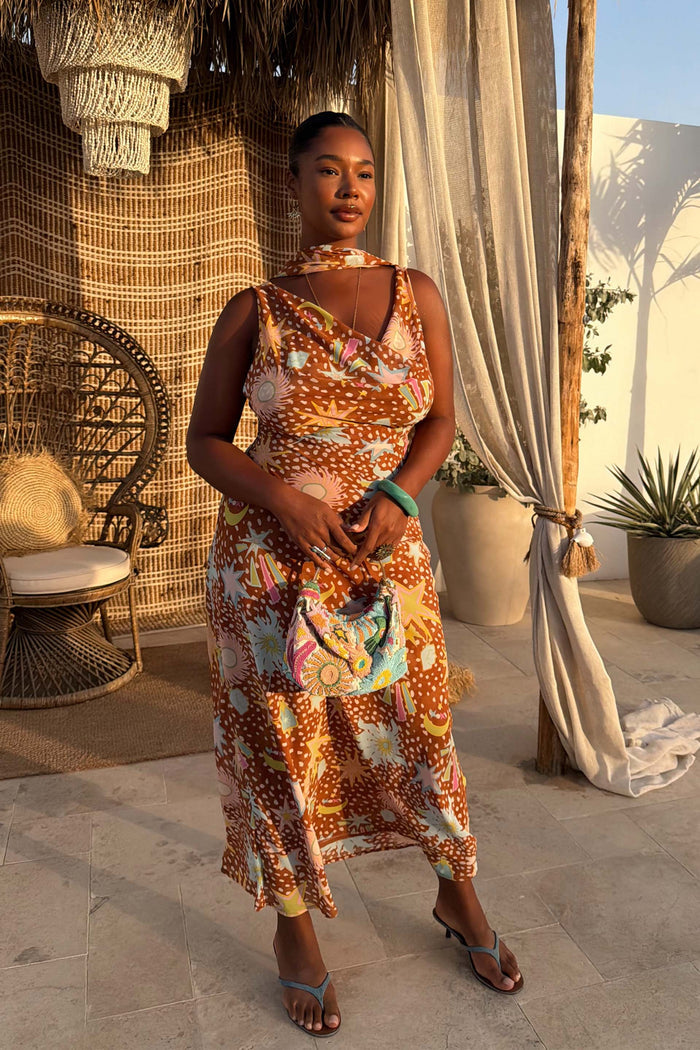 Star Fawn Sophie Dress in brown with sun and palm motifs and a multi-wear neck scarf on a model.