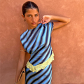 Stripe A-Symmetrical Top in blue diagonal print with yellow lace trim, shown against a terracotta wall.