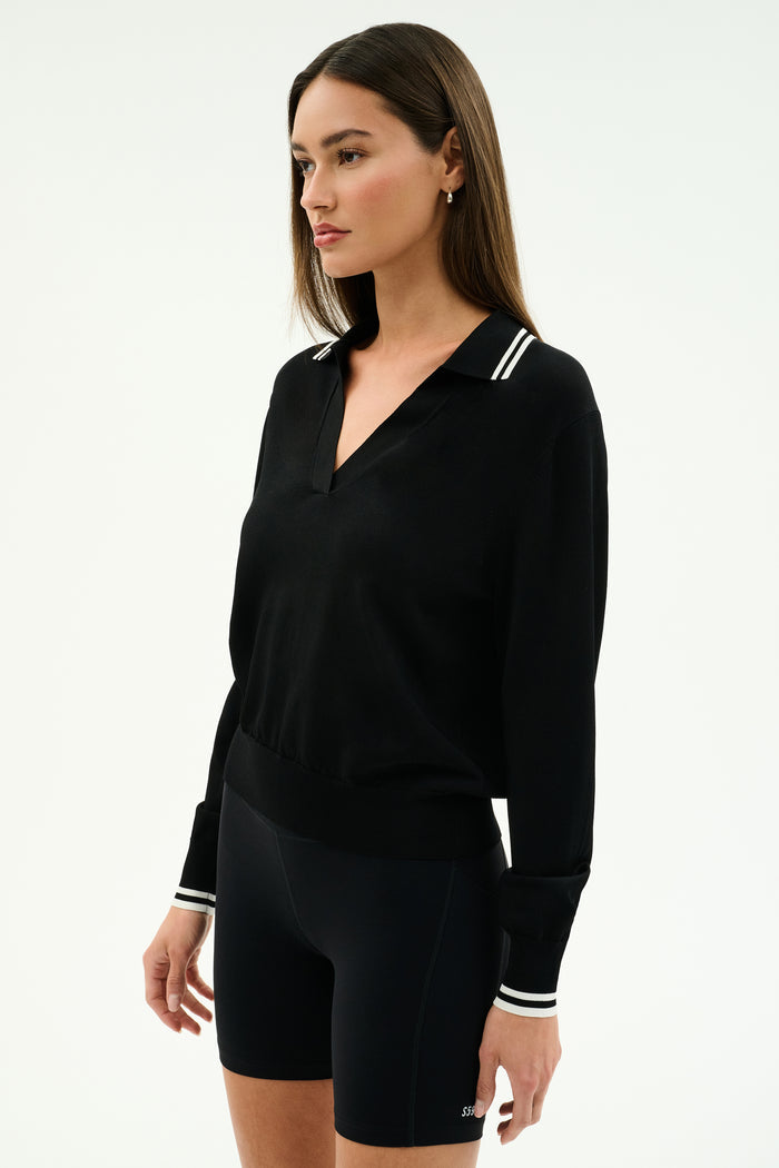 A woman wears the SPLITS59 Taylor Knit Polo in black/white and black fitted shorts, standing against a plain white background.