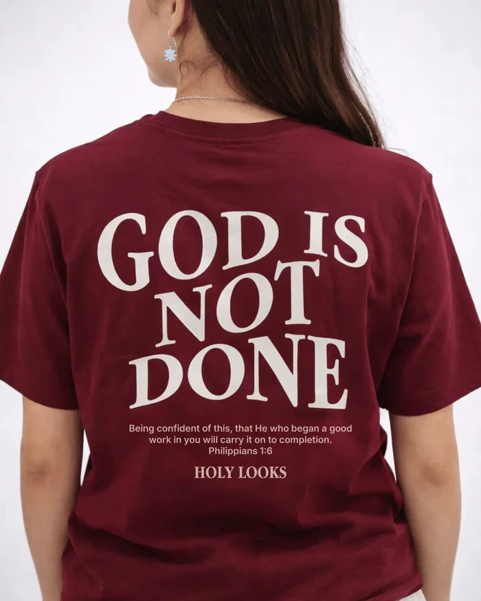 Maroon t-shirt with 'God is Not Done' text on the back, worn by a person.
