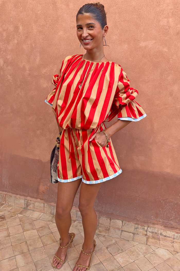 Model wearing the red and camel Tomato Stripe Blouse and matching shorts co-ord with voluminous sleeves and blue trim.