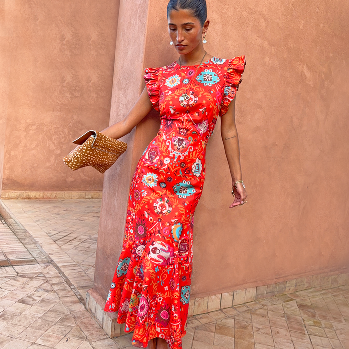 Red Tomato Tapestry Frida Dress with sun motifs and ruffle sleeves, styled with a spotted clutch bag.