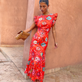 Red Tomato Tapestry Frida Dress with sun motifs and ruffle sleeves, styled with a spotted clutch bag.