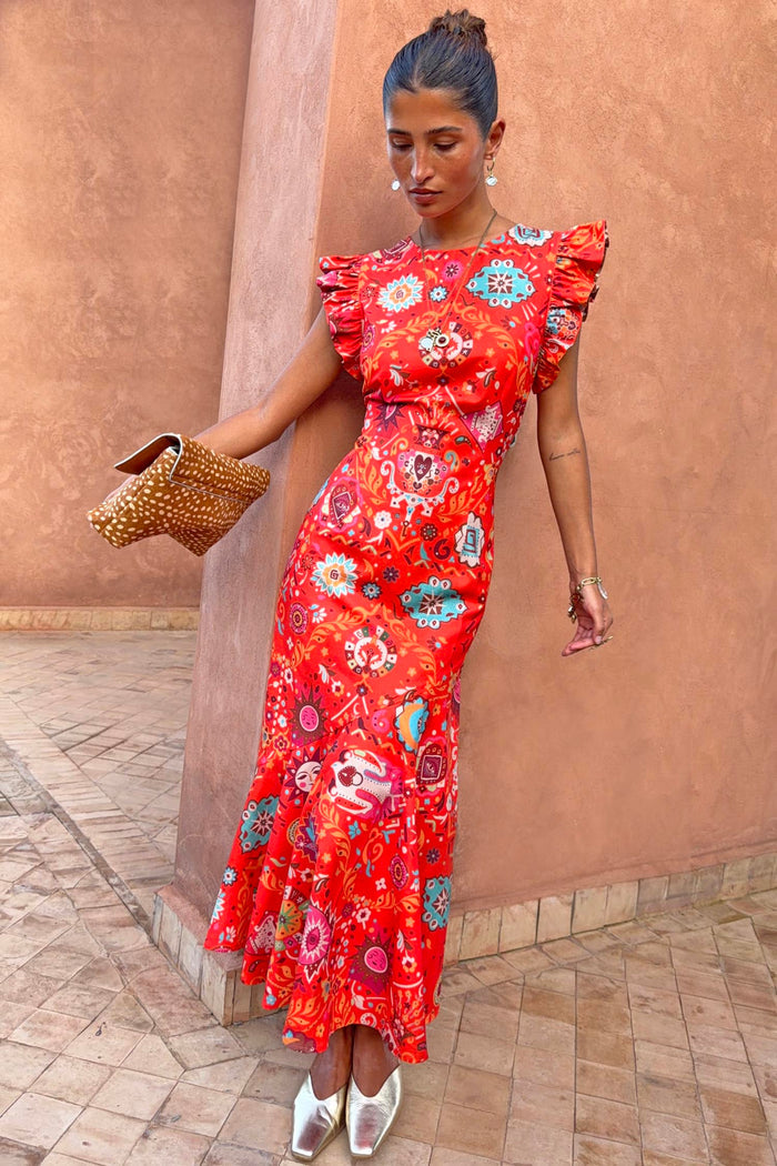 Tomato Tapestry Frida midi dress in red featuring sun motifs and ruffle sleeves, styled with gold mules.