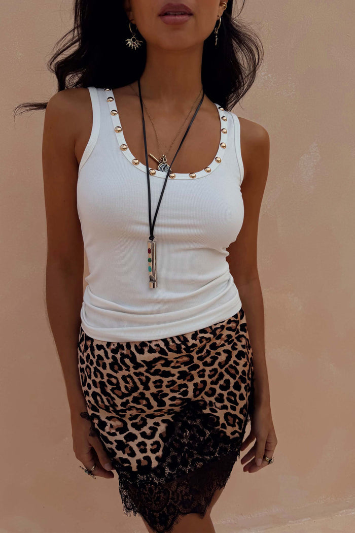 White ribbed vest with gold stud detailing along the neckline, styled with a leopard print lace skirt.
