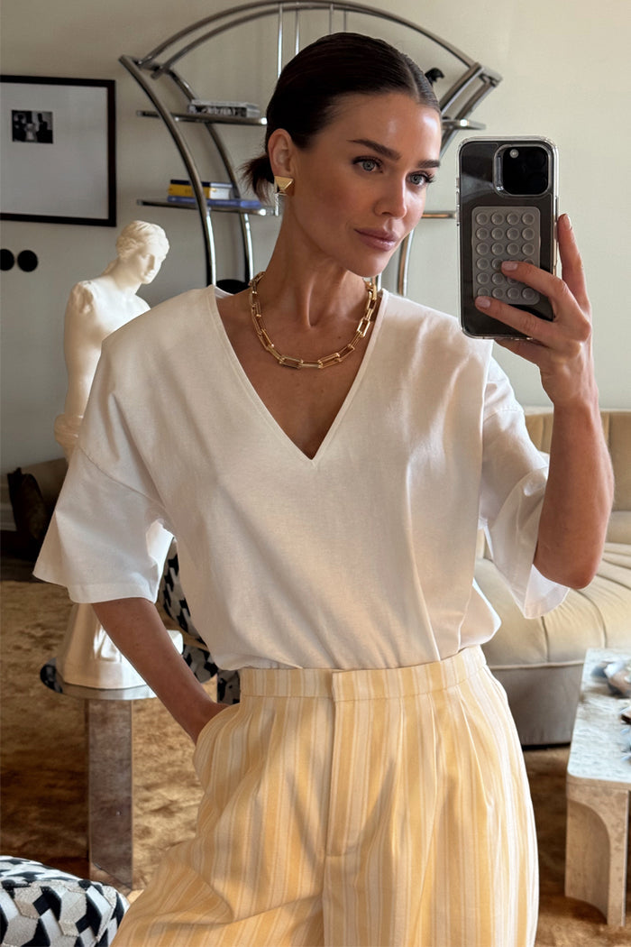 White T Shirt with Shoulder Pads and a deep V-neck, styled with yellow striped trousers in a mirror selfie.