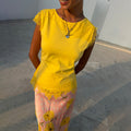 Yellow Lace Insert Top featuring lace cap sleeves and a scalloped asymmetric hem, styled with a patterned pink skirt.