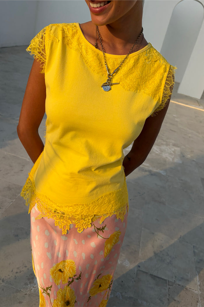 Yellow Lace Insert Top featuring cap lace sleeves and an asymmetric hem, paired with a floral skirt.