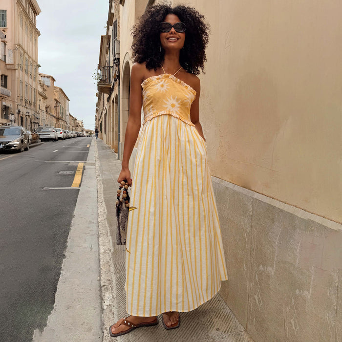 Yellow Stripe Ashley Dress in cotton-linen with sun motifs and a bandeau top, styled for a vacation look.