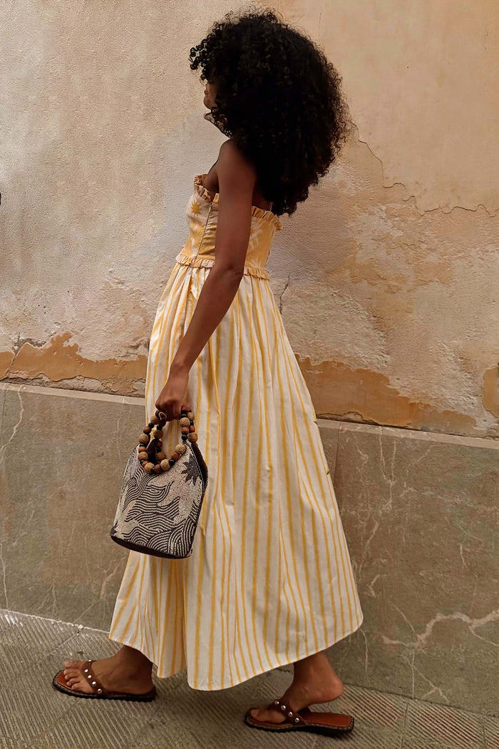 Yellow Stripe Ashley Dress with vertical yellow stripes and a ruffled bandeau top, shown on a model walking.