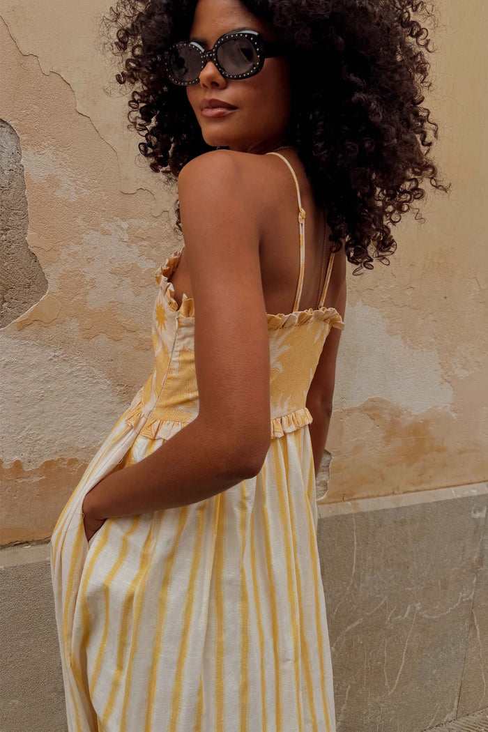 Yellow Stripe Ashley Dress with sun motifs, frilled trims and side pockets in a cotton-linen blend on a model.