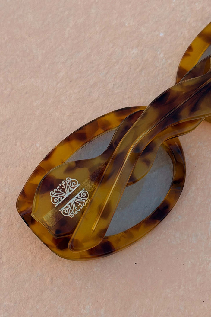 Yellow Tort Wiggle Arm Sunglasses with a wavy tortoise shell frame and signature white branding.